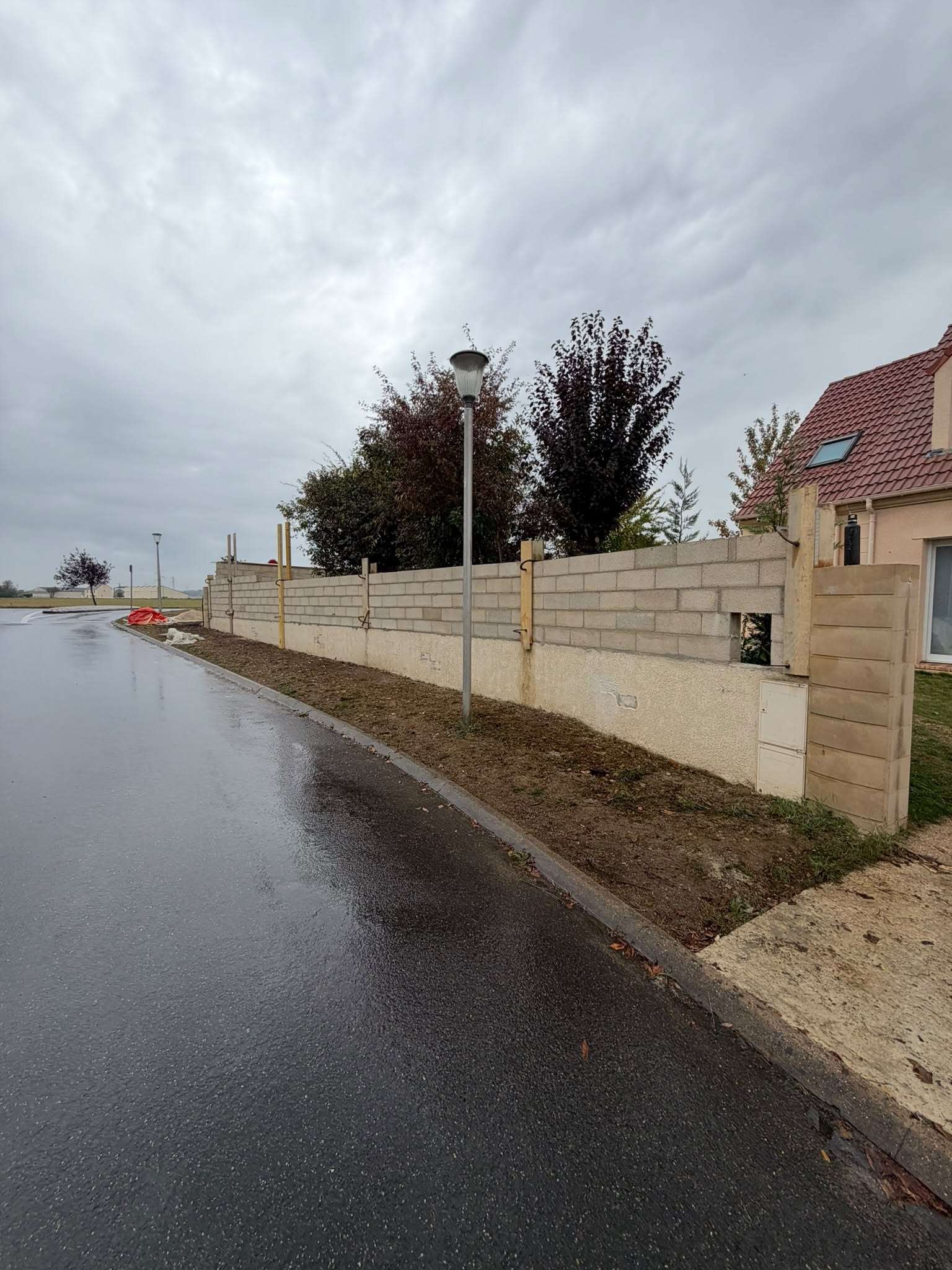 Mur de clôture en blocs béton en cours d’élévation le long d’un trottoir